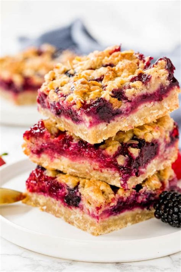 Berry crumble bar on a white plate with a scoop of ice cream.